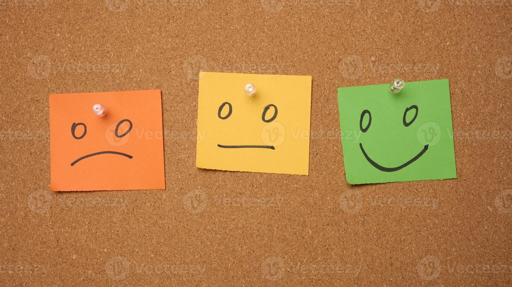 Drawn faces with different emotions on a sticker and attached to a cork board. Rating and quality assessment photo