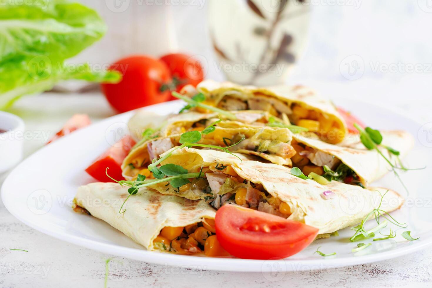 Mexican Quesadilla wrap with chicken, corn and sweet pepper on white plate. photo