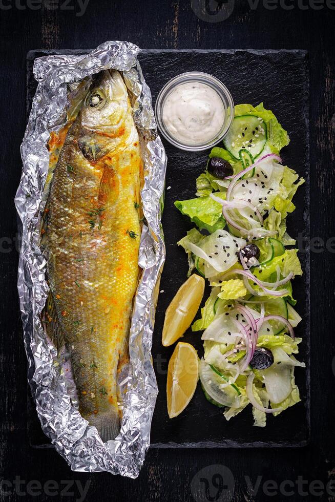 Baked sea bass and green salad. Healthy eating. Keto, ketogenic diet. Top view photo