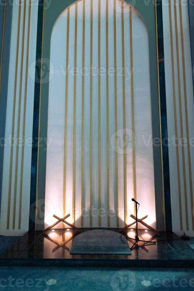 Mihrab of a modern mosque with microphone and book stands photo