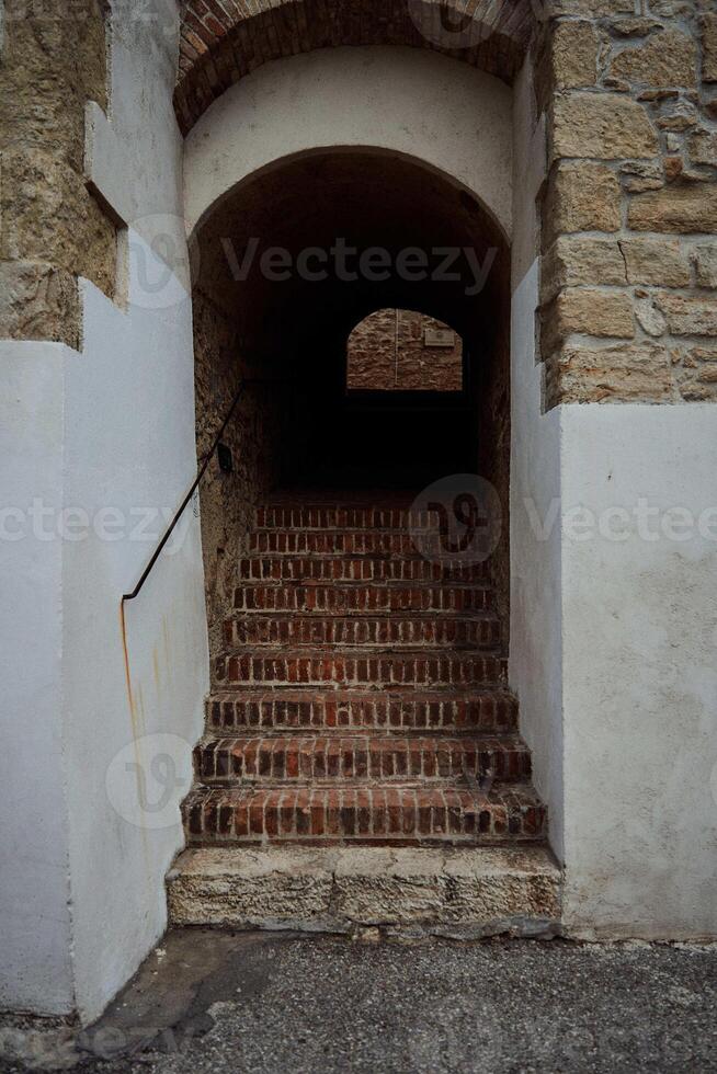 an arch with stairs in the wall of a stone house photo