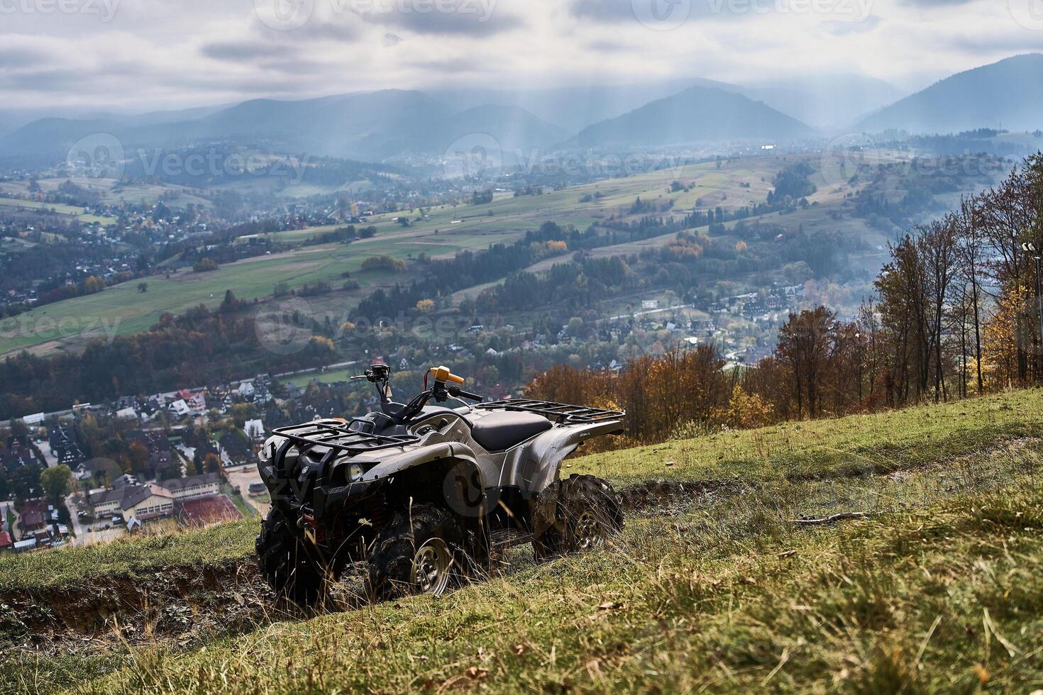 Gray quad bike on the mountain slope overlooking the city below photo