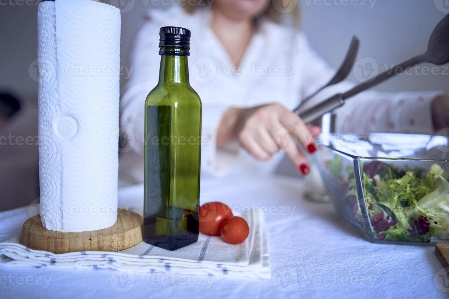 a teenage girl and her mother in pajamas are cooking and eating a fresh green and tomato salad together photo