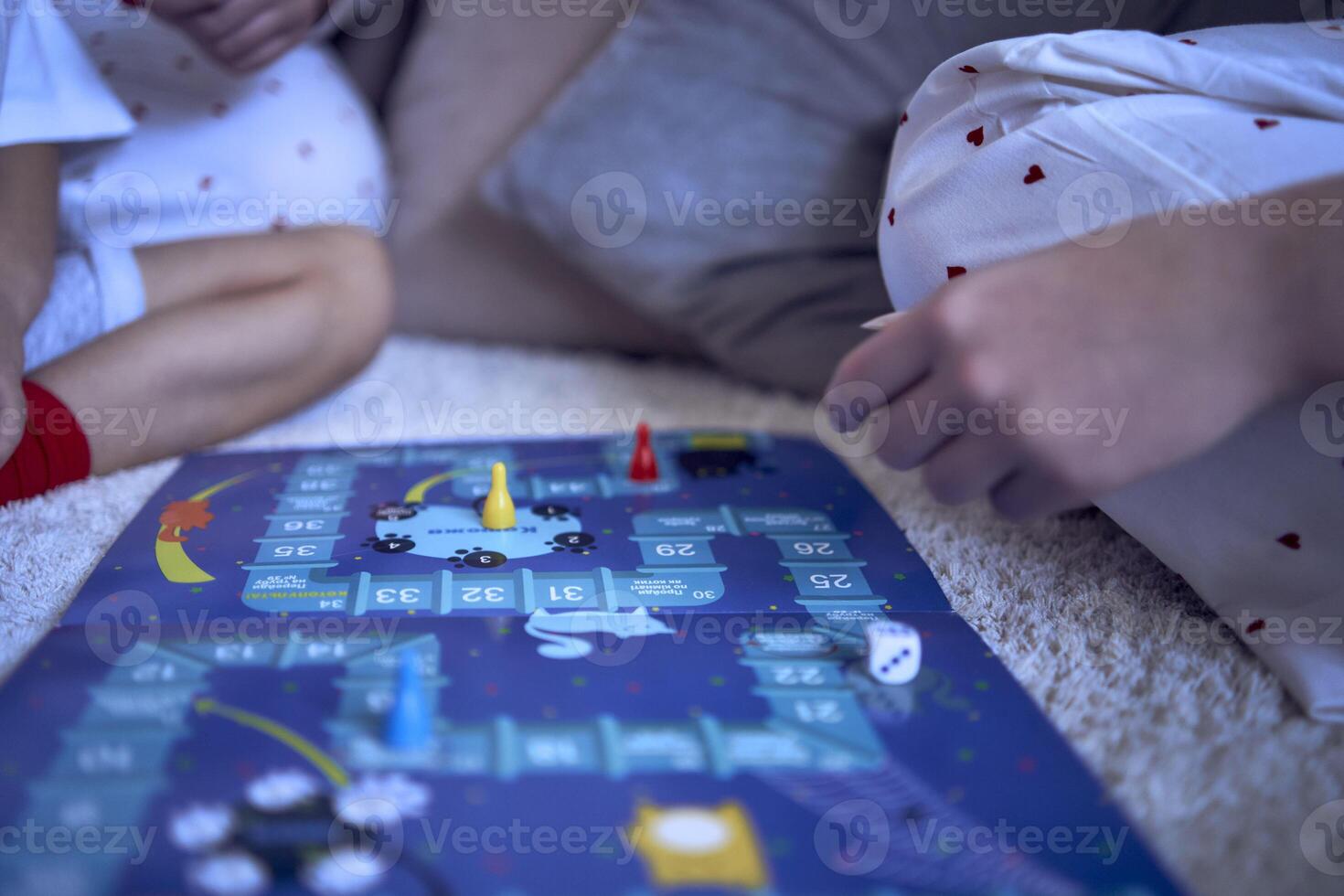 mother with teenage daughter and little son in pajamas playing board games on the floor photo