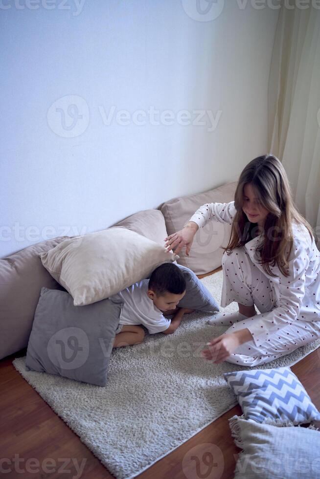 un Adolescente niña construye un fortaleza fuera de almohadas para su pequeño hermano foto