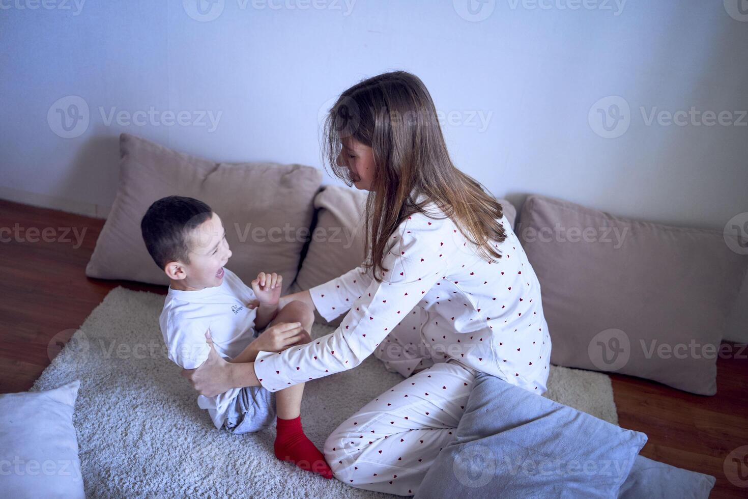 teenage girl and her little brother are playing and hugging in a pillow fort photo