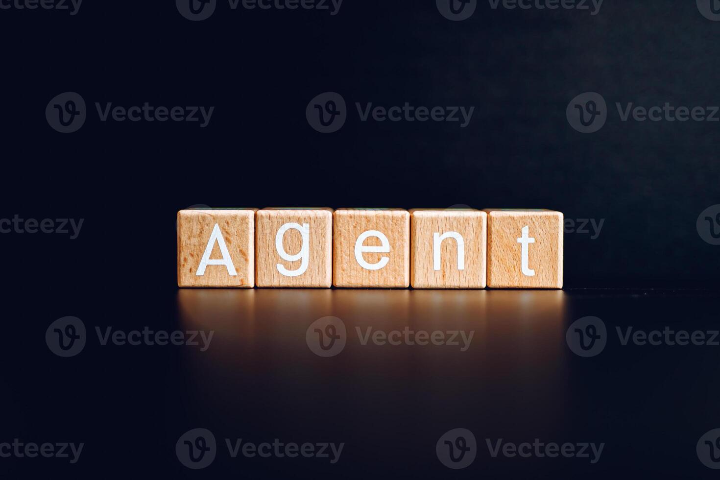 Wooden blocks form the text Agent against a black background. photo