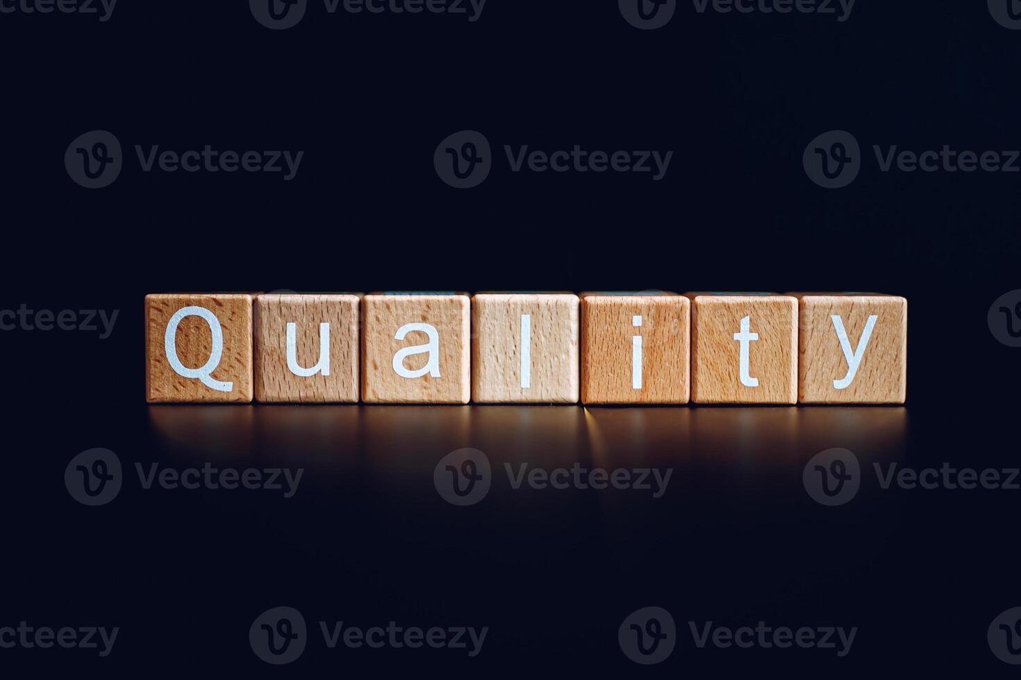 Wooden blocks form the text Quality against a black background. photo