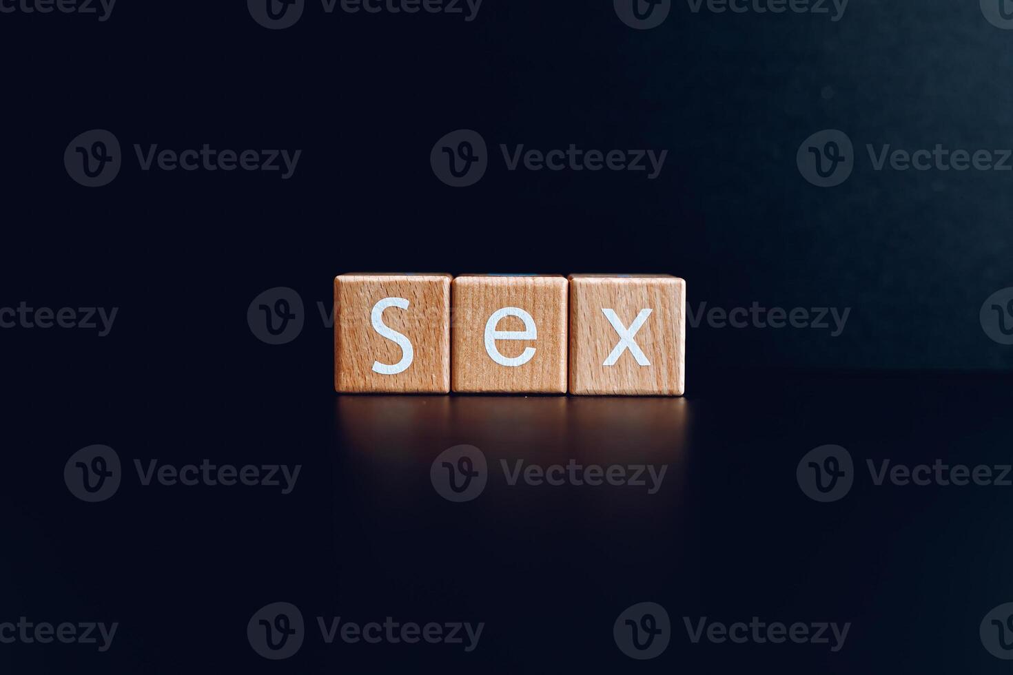 Wooden blocks form the text Sex against a black background. photo