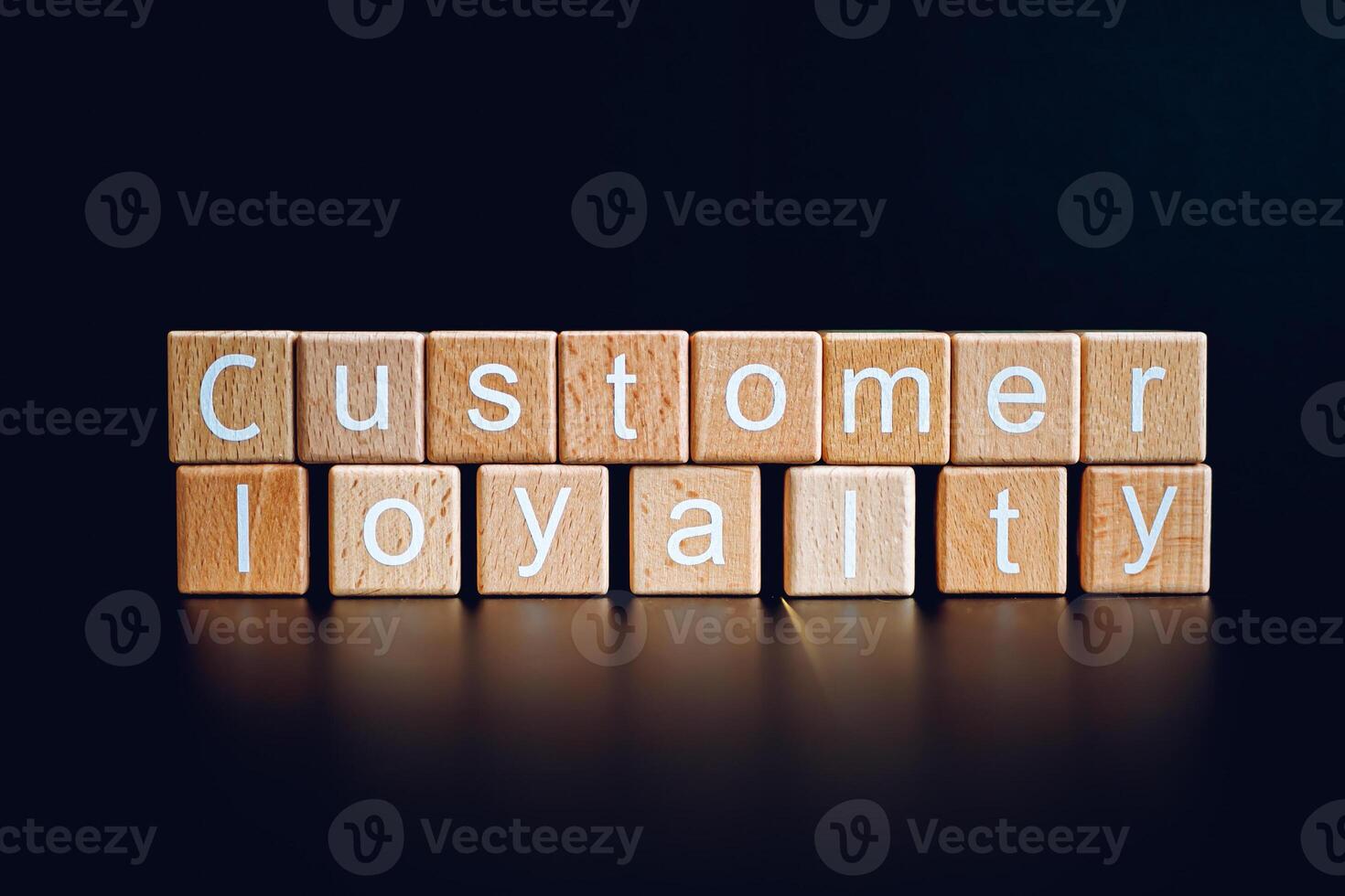 Wooden blocks form the text Customer loyalty against a black background. photo
