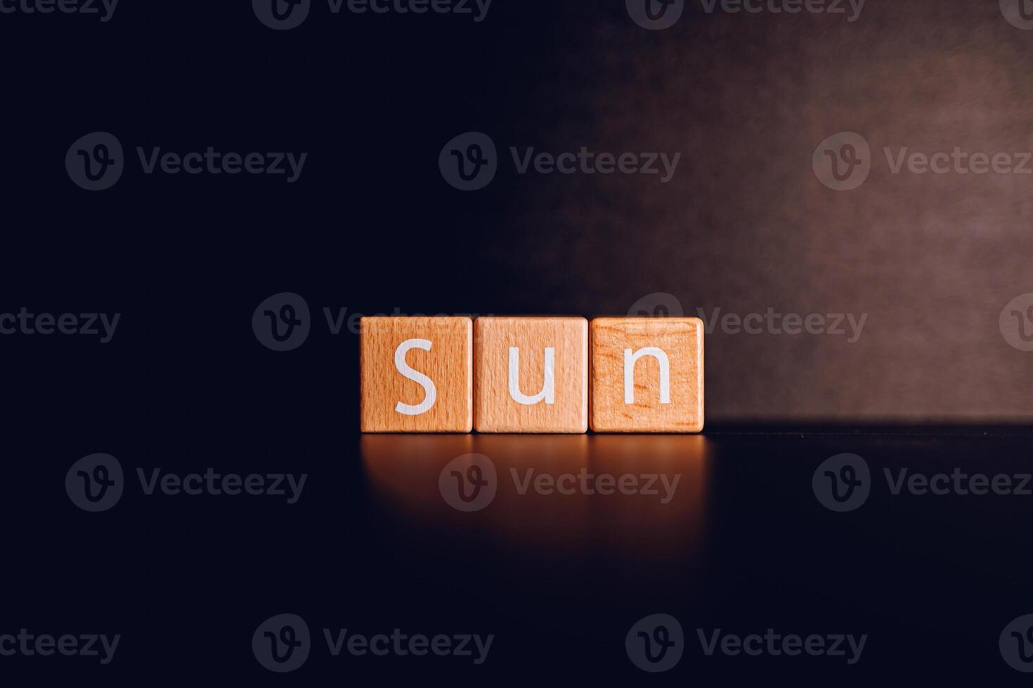 Wooden blocks form the text Sun against a black background. photo