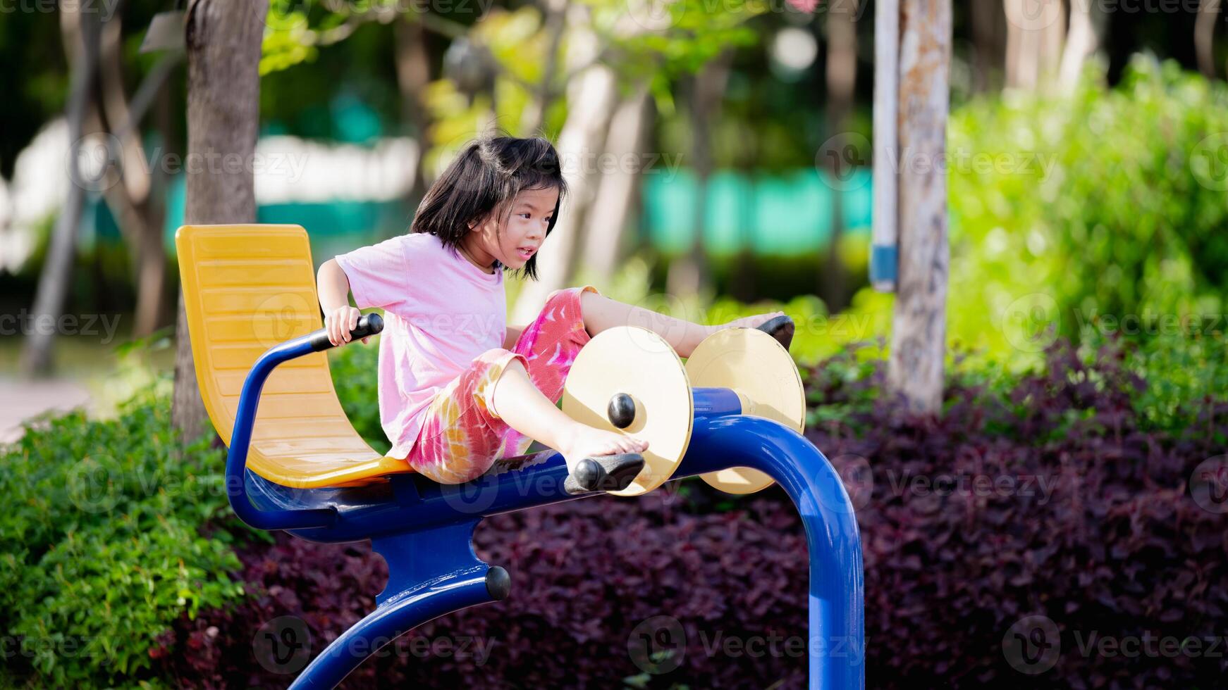 positivo imagen representa asiático niño niña disfrutando sí mismos en pierna ejercicio máquina en el parque, Copiar espacio, en verano o primavera veces, contento niño Envejecido 6 6 años viejo, activo niños dulce sonrisa. foto