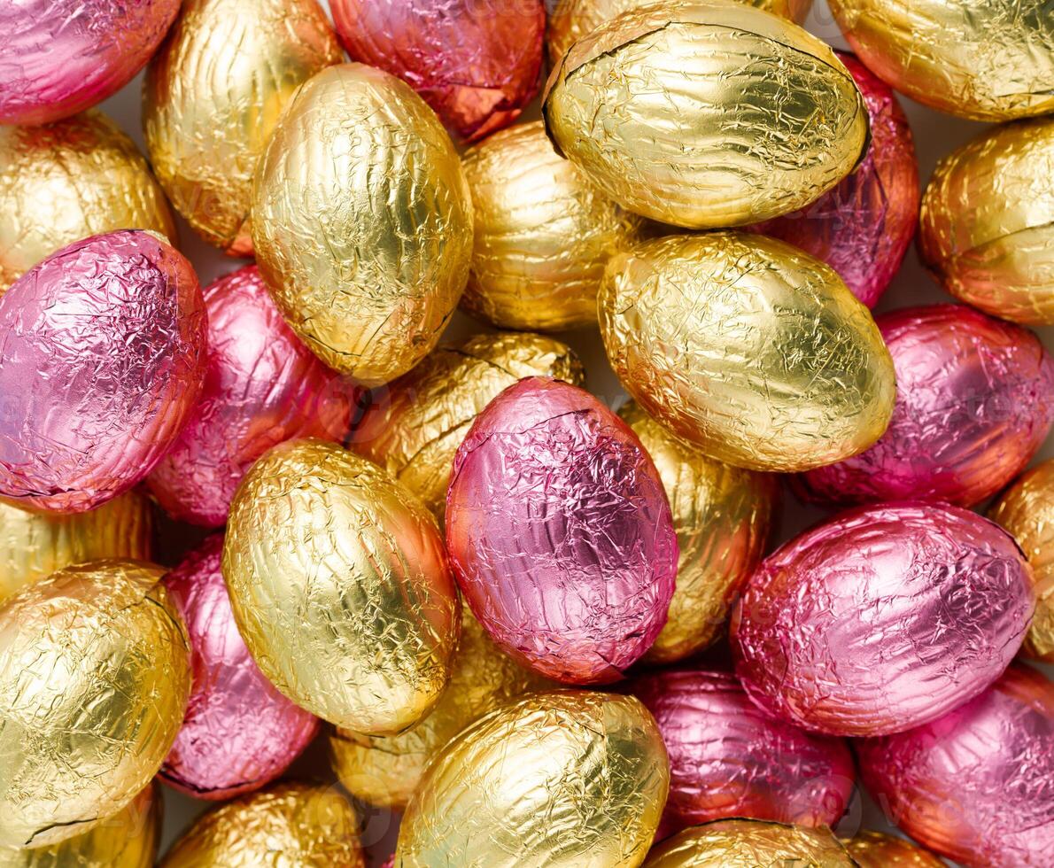 Close-up of pile of Easter candy eggs wrapped in pink and golden foil photo