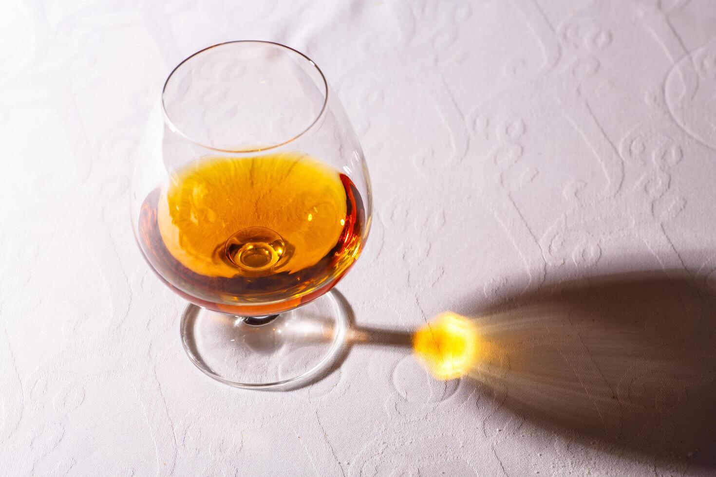 The glare from the glass of French brandy reflected on white tab photo