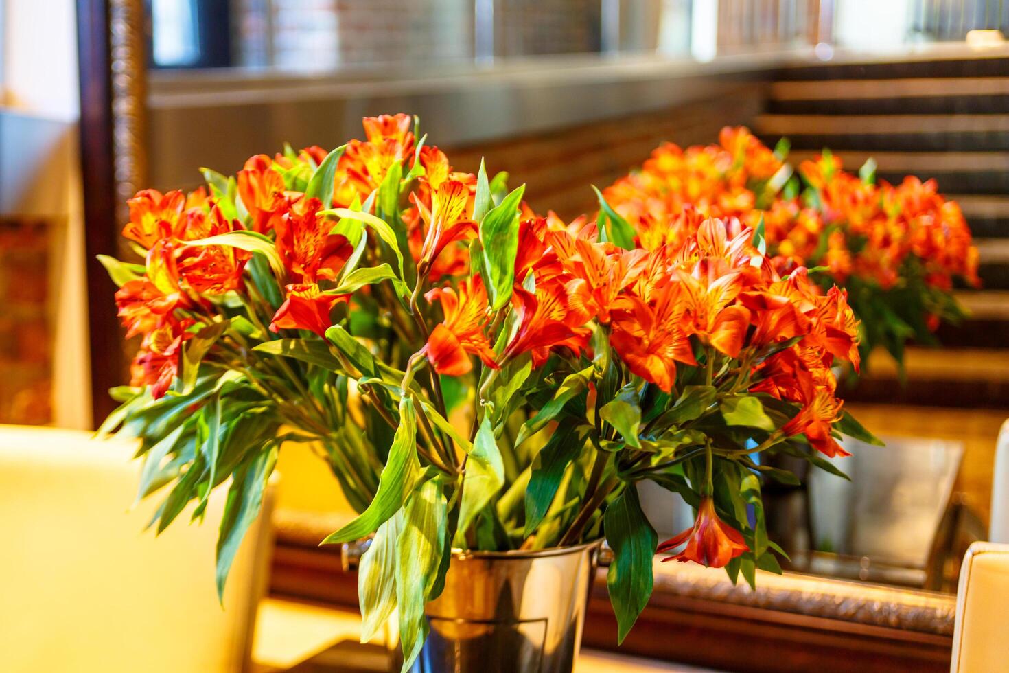 Red flowers in a vase reflected in the mirror, it's funny. photo