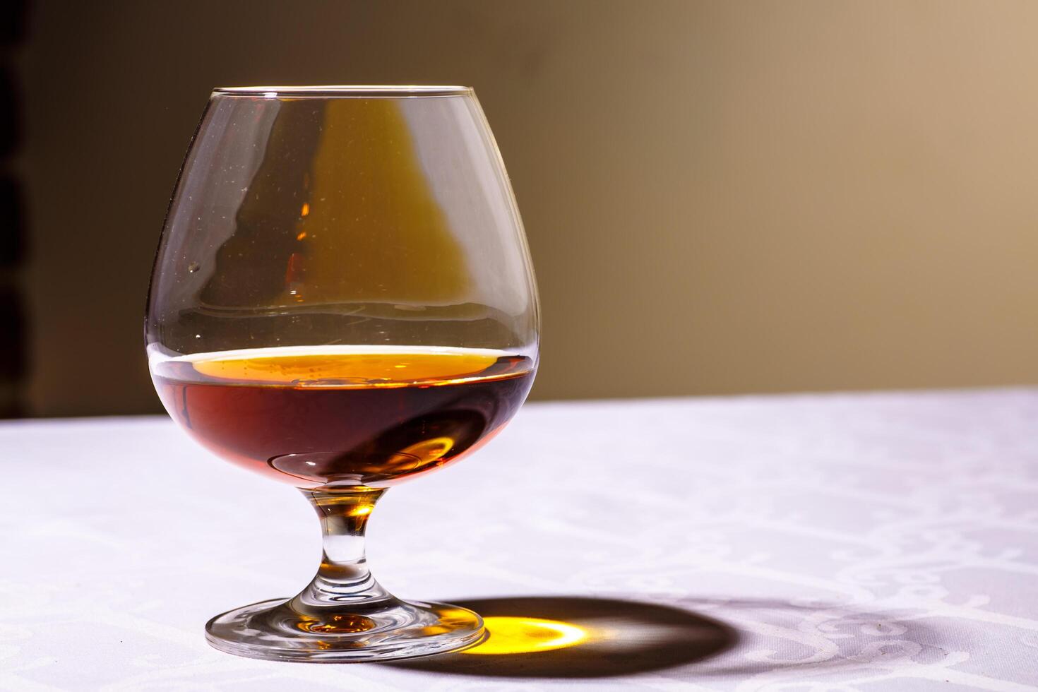 The glare from the glass of French brandy reflected on white tab photo