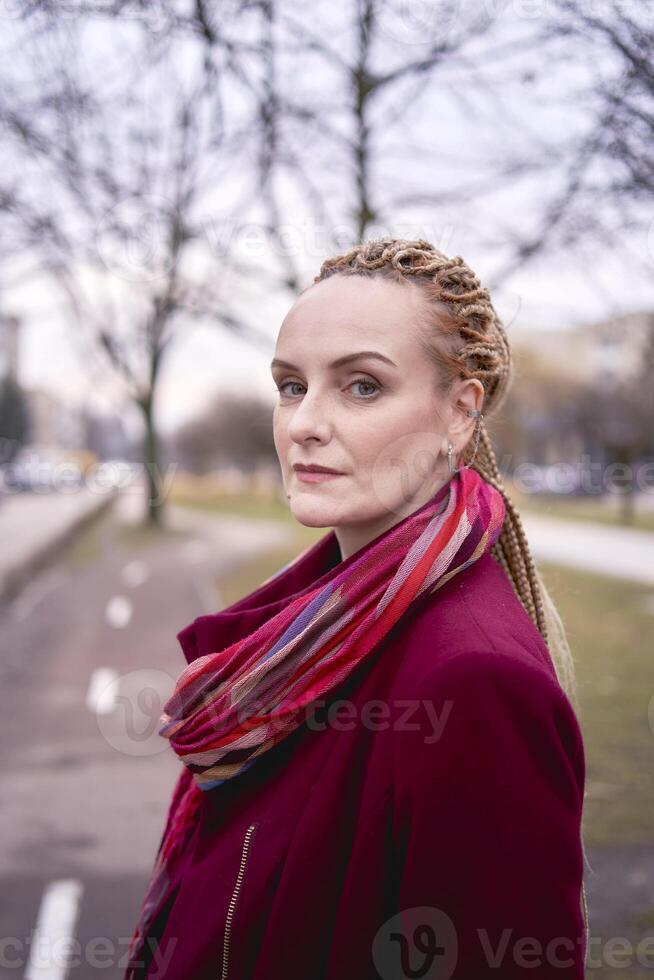 portrait of a stylish middle-aged woman with braids on a spring street photo