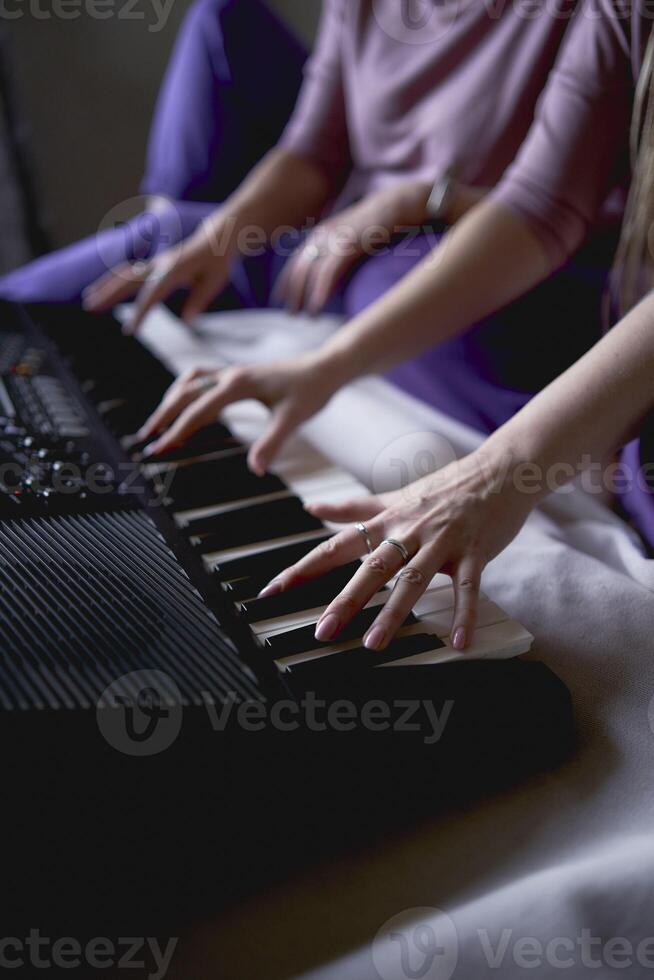 A 60-year-old mother and a 40-year-old daughter play the keyboard together on the bed at home photo