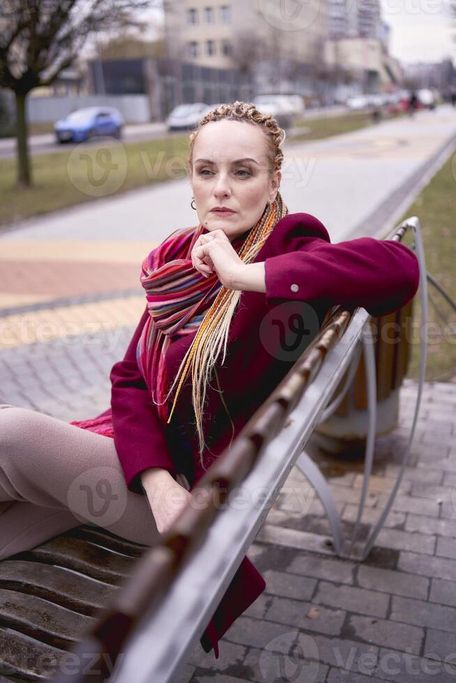 retrato de un elegante de edad mediana mujer con trenzas en un primavera calle foto