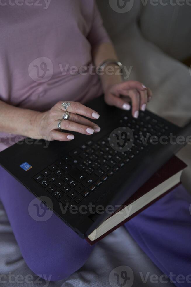 un mayor mujer trabajos con ordenador portátil a hogar foto