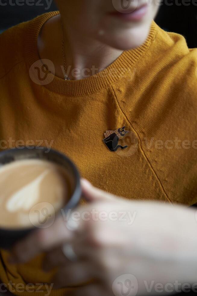 retrato de un elegante de edad mediana mujer en un amarillo suéter Bebiendo café en un café foto