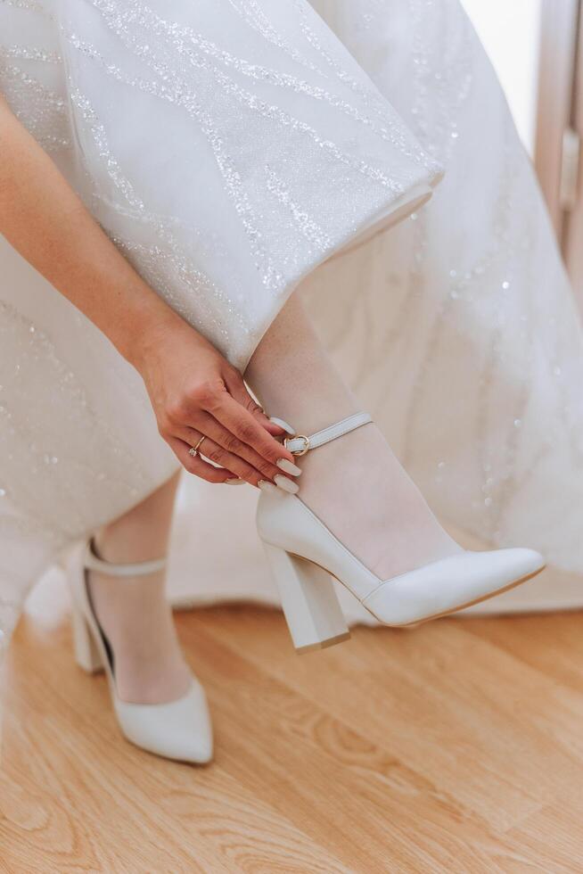 Bride's shoes. The girl wears stilettos. Elegant women's shoes. Beautiful details. The bride puts on her shoes and prepares for the wedding ceremony photo