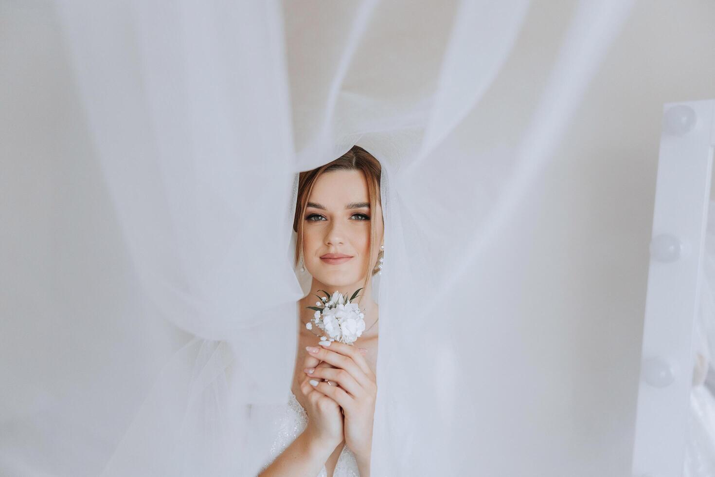 Portrait of the bride in the hotel room. A beautiful young girl is dressed in a white wedding dress. Modern wedding hairstyle. Natural makeup. photo