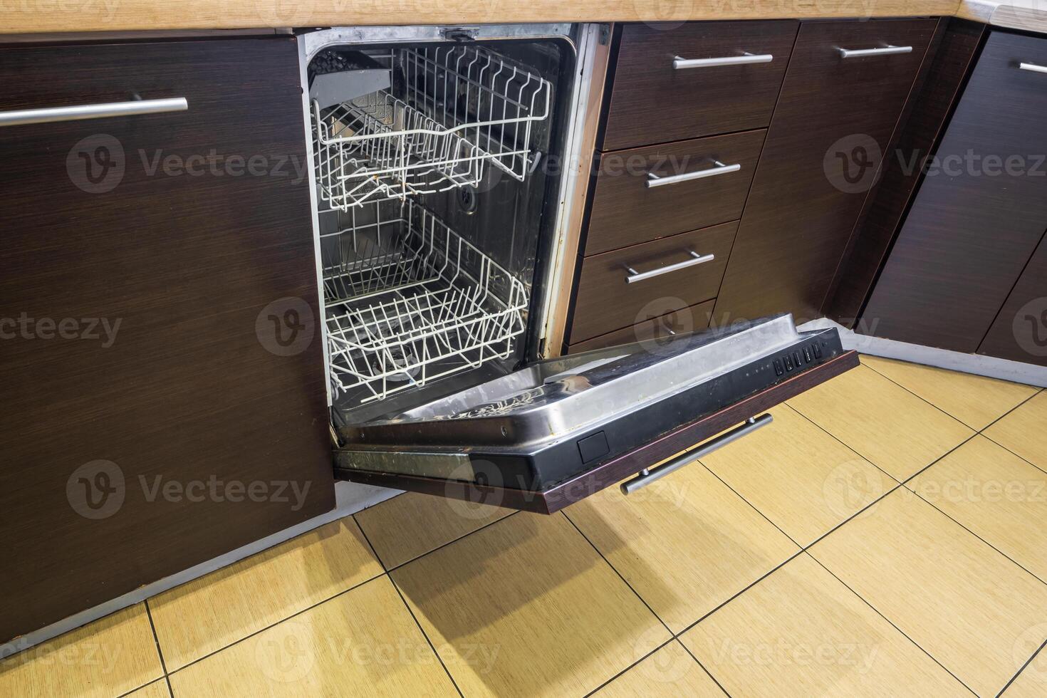 open door of an empty dishwasher in the kitchen photo