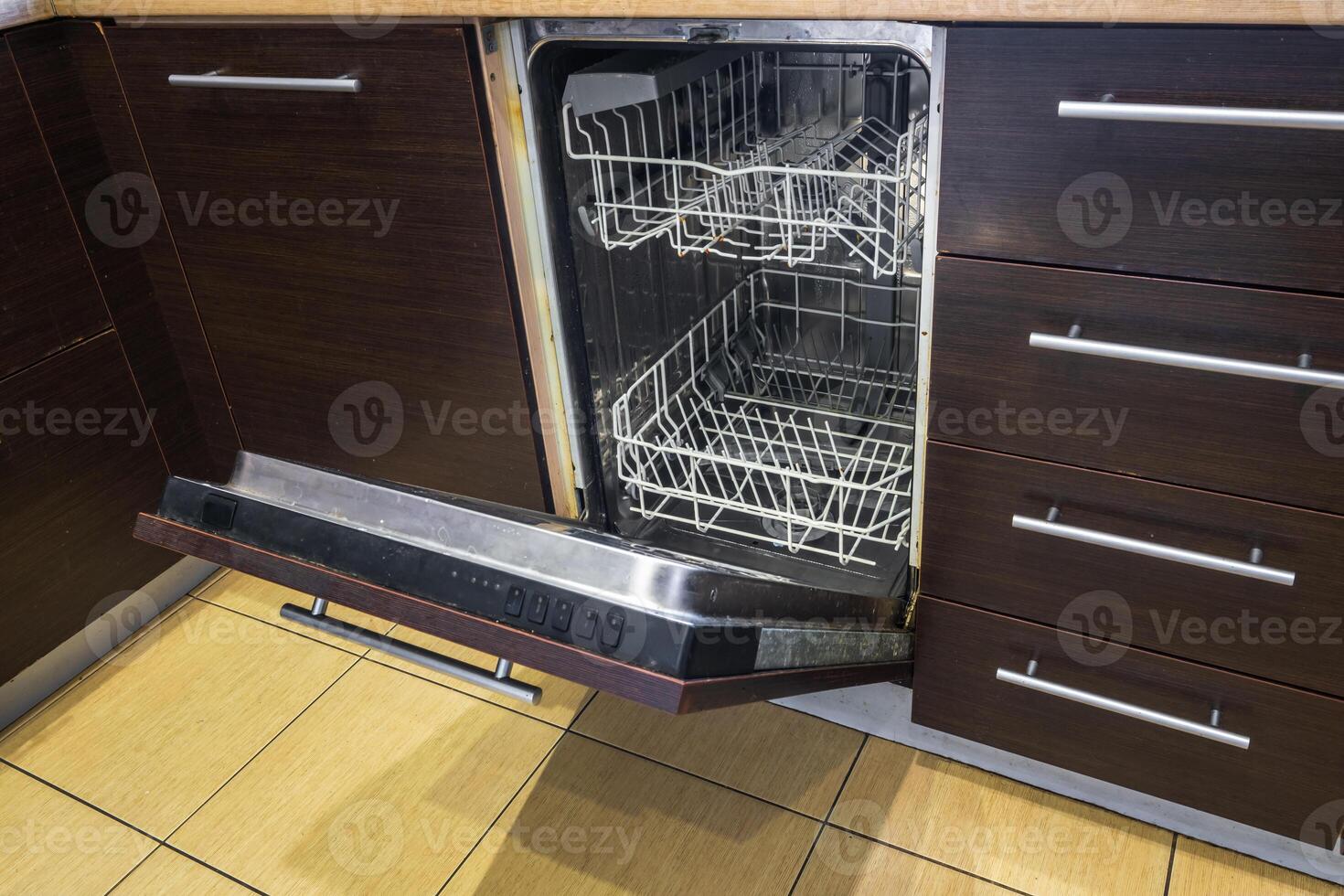 open door of an empty dishwasher in the kitchen photo