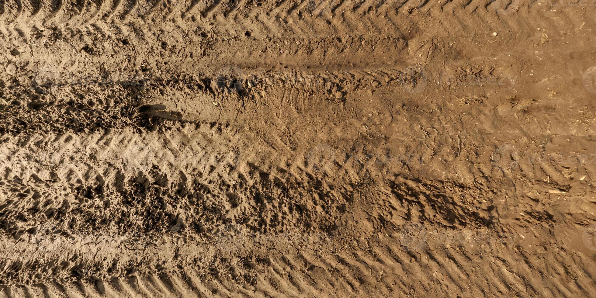 panorama of muddy road from above on surface of wet gravel road with tractor tire tracks in countryside photo