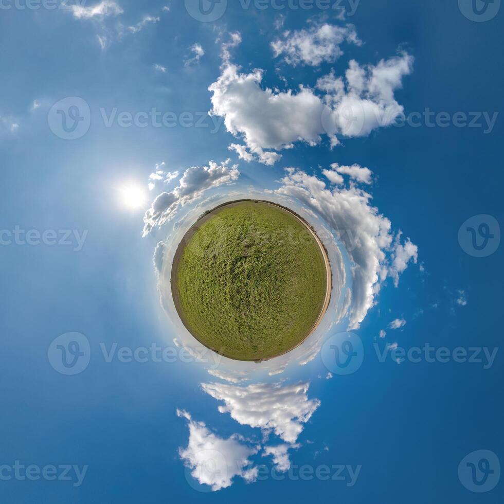 simple green tiny planet without buildings in blue sky with beautiful clouds. Transformation of spherical panorama 360 degrees. Spherical abstract aerial view. Curvature of space. photo
