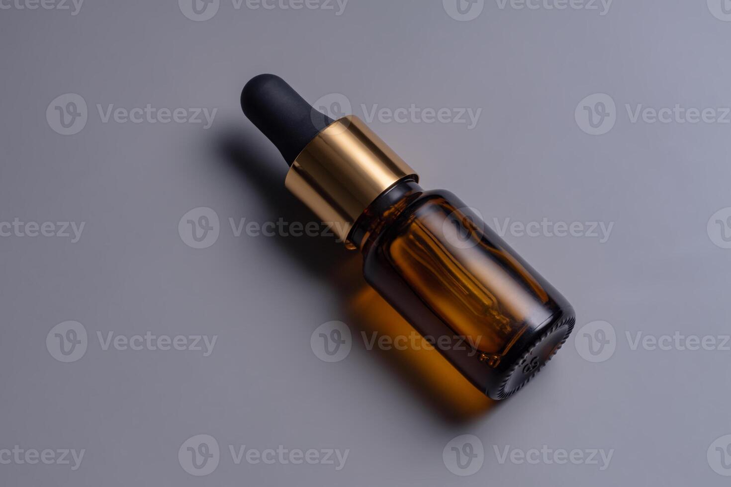 Amber glass cosmetic dropper bottle with blank label on grey background. Trendy beauty product design, branding. Mockup cosmetics photo