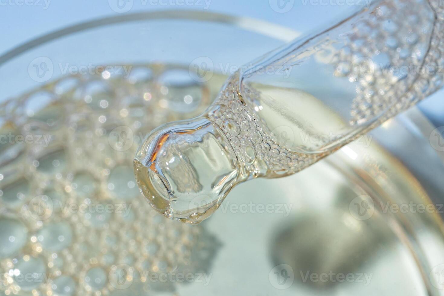 Bottle pipette dropper close up and Liquid yellow-orange retinol or vitamin c gel or serum on a blue background photo