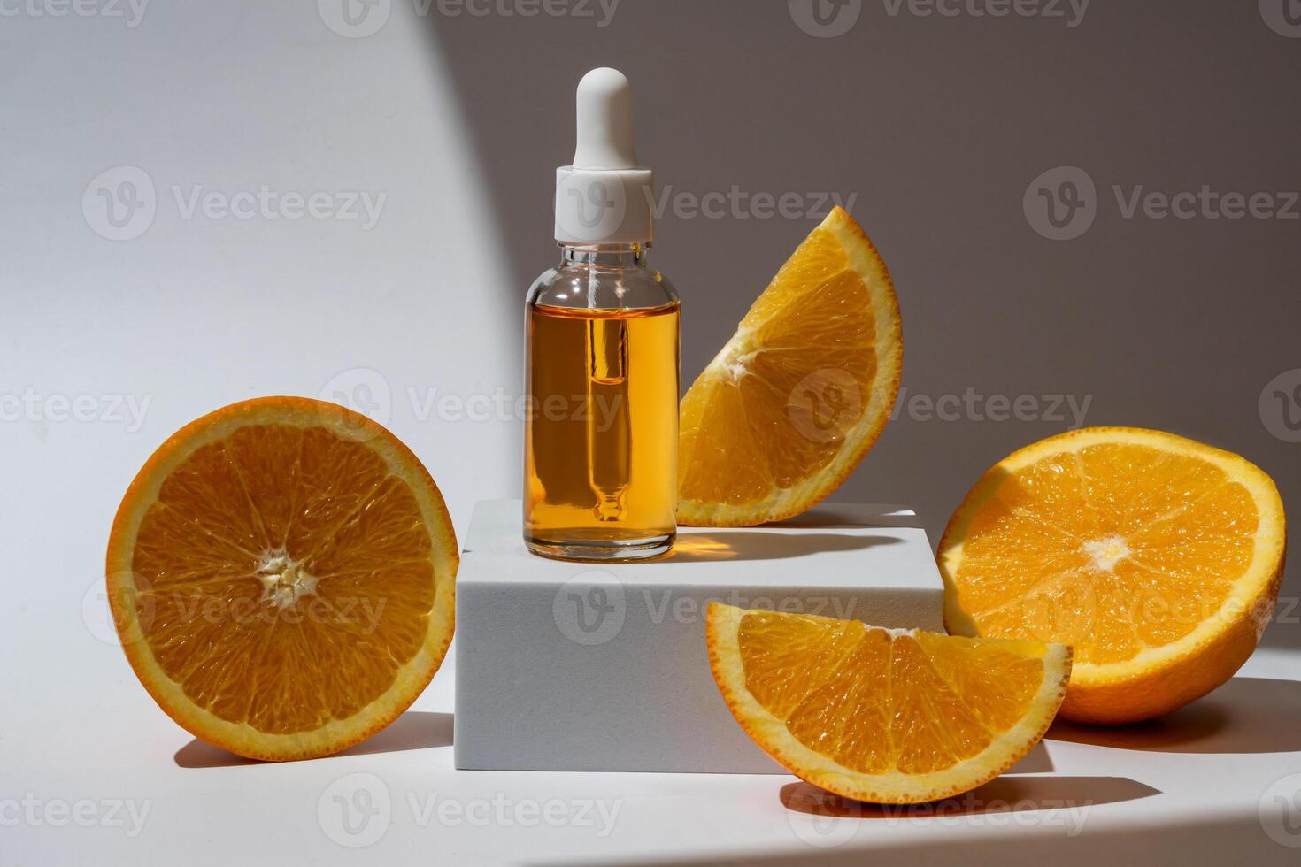 Glass bottle with an orange oil dropper for skin, hair. Packaging with serum on white background in rays of sunlight. Container with cosmetics for skin care on a podium. Concept of mockup, branding. photo