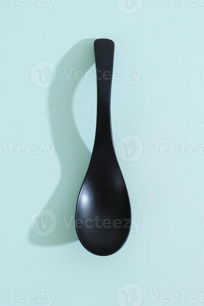 Black Wooden Spoon on Mint Background photo