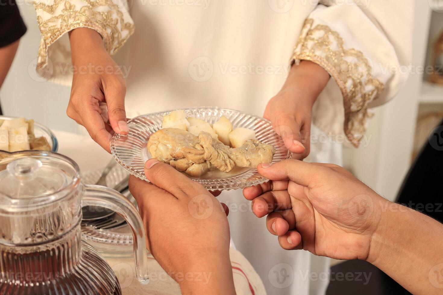 Female Hand Serve Plate of Food with Ketupat and Opor photo