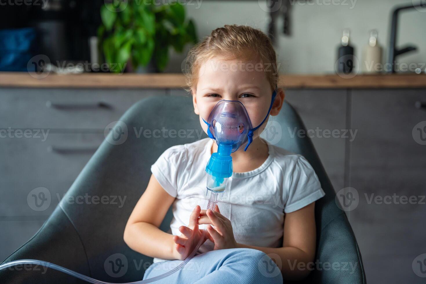 Crying little girl are sitting and holding a nebulizer mask leaning against the face, airway treatment concept photo