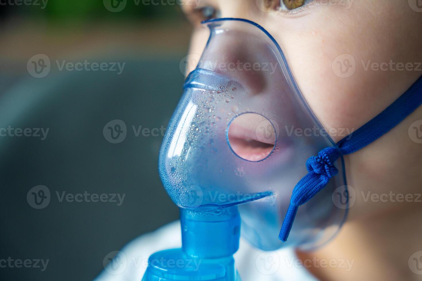 cerca arriba ver de pequeño niña son sentado y participación un nebulizador máscara propensión en contra el rostro, vías respiratorias tratamiento concepto foto