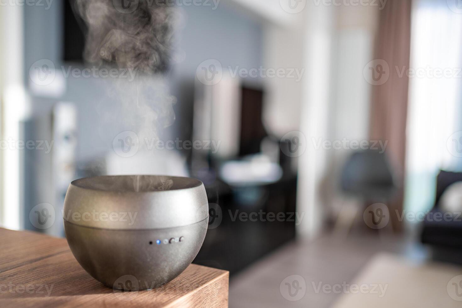 Grey aroma oil diffuser on light table at home, space for text. Air freshener photo