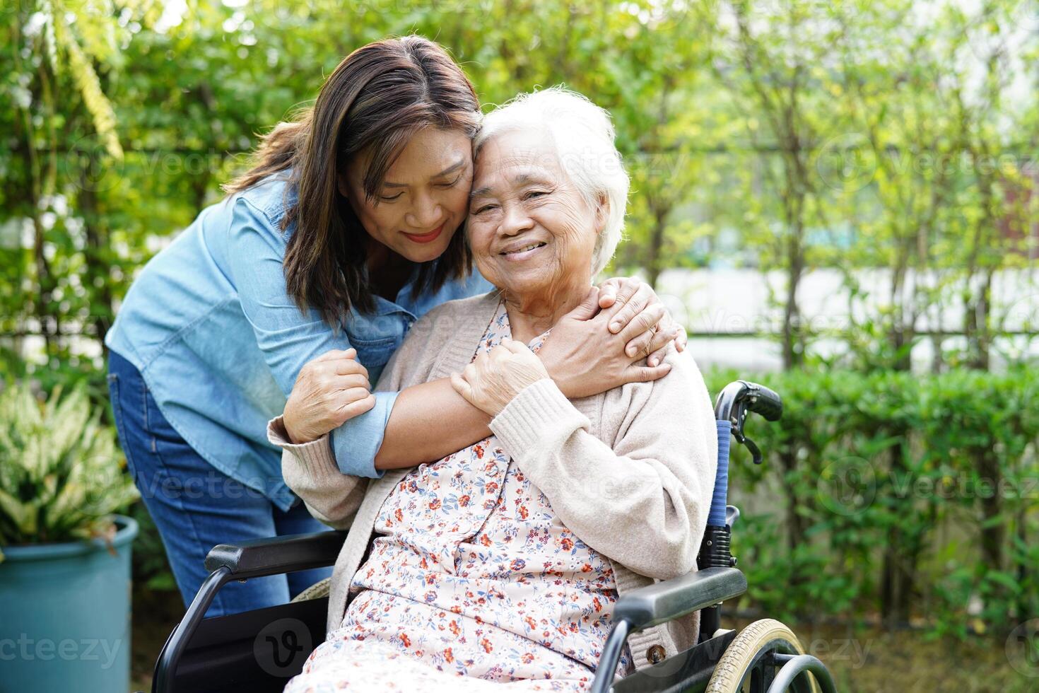 Caregiver help Asian elderly woman disability patient sitting on wheelchair in park, medical concept. photo