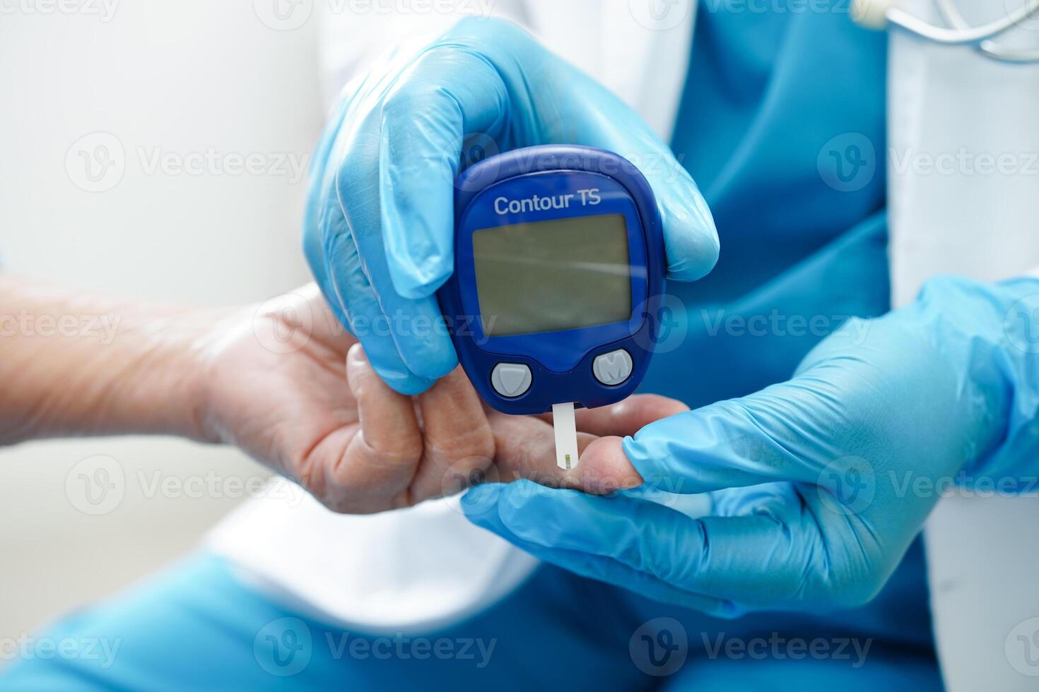 Asian doctor using digital glucose meter for check sample blood sugar level to treatment diabetes. photo