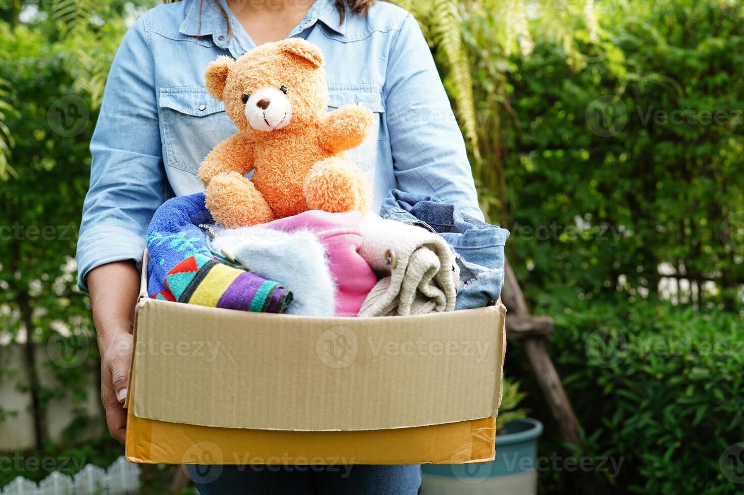 Volunteer collect cloth and doll in cardboard box to donate. photo