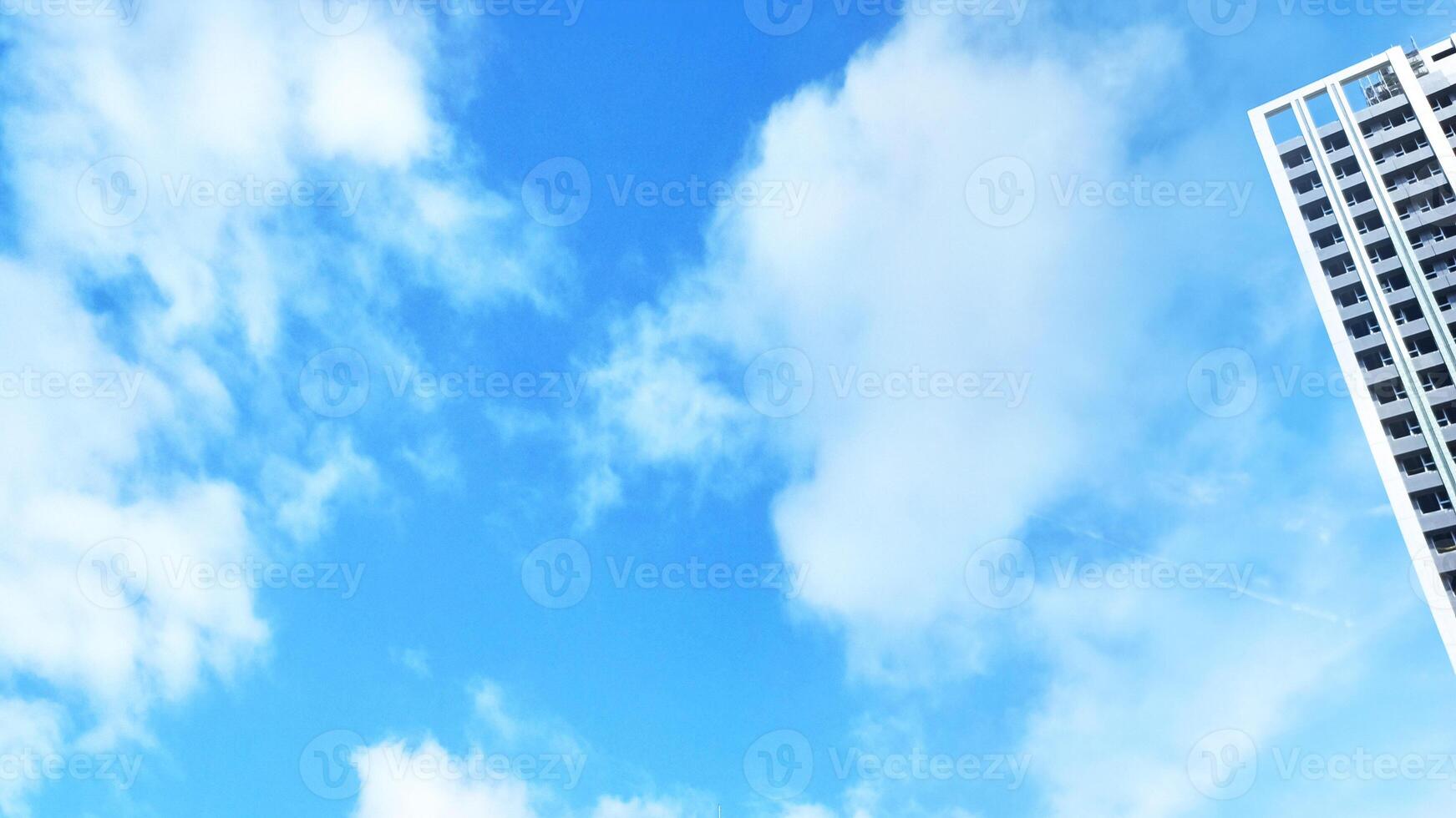 High rise buildings stand beside the blue sky and white clouds photo