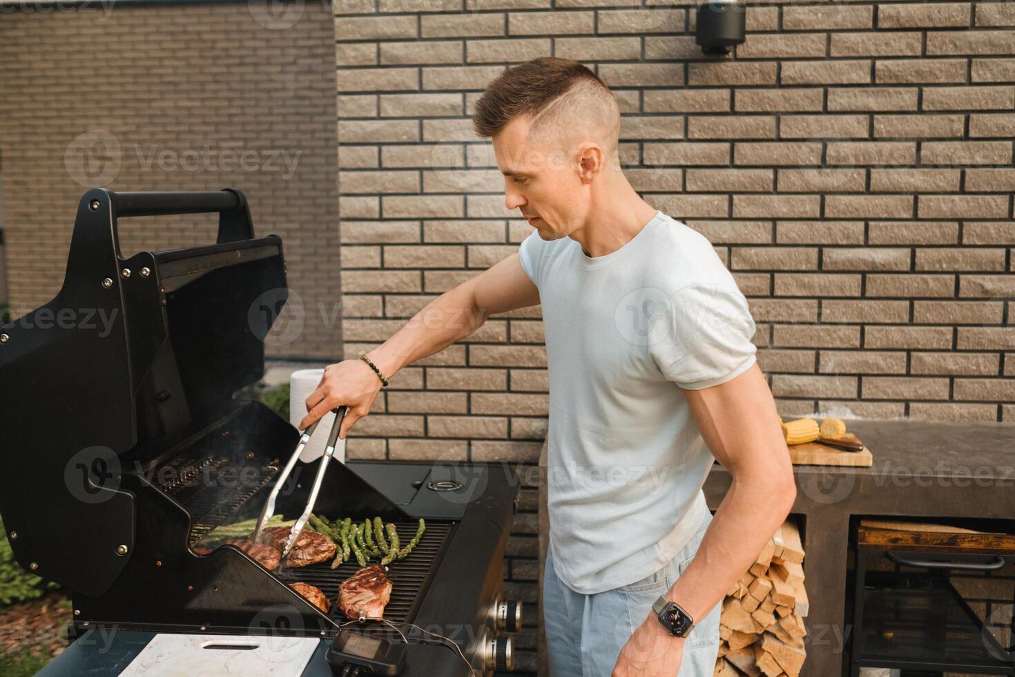 A man on the street is cooking a steak on the grill at a barbecue photo