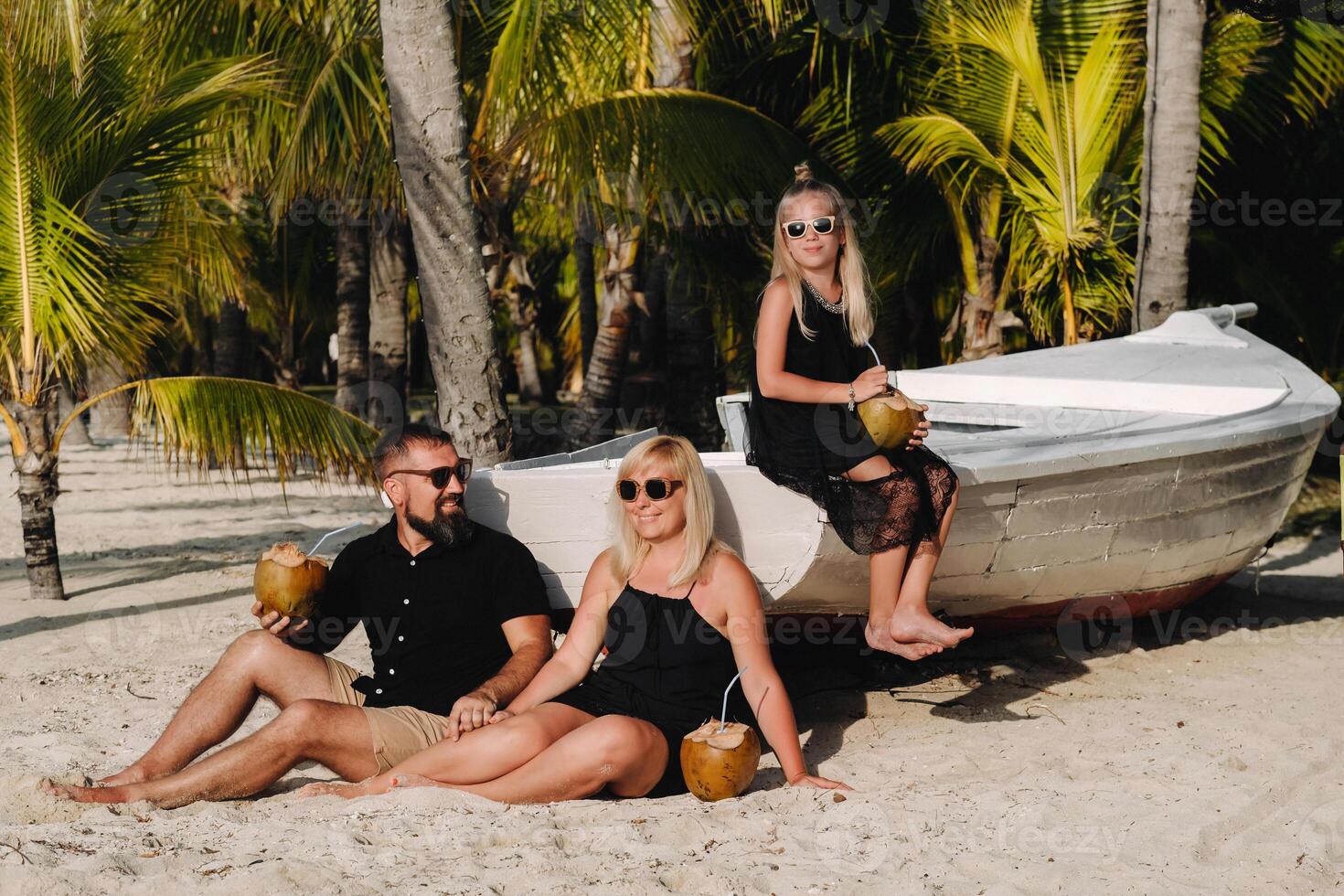 un elegante familia en negro ropa con cocos en su manos en el playa de el isla de mauricio.hermoso familia en el isla de Mauricio en el indio Oceano foto