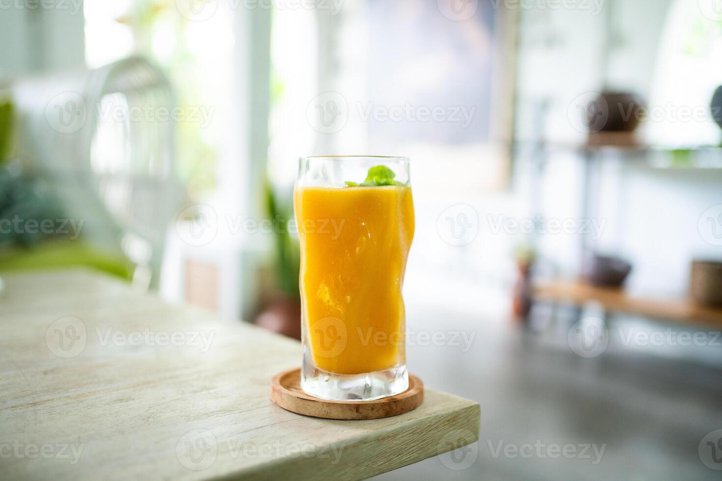 Fresh mango juice on table with luxury home blur background photo