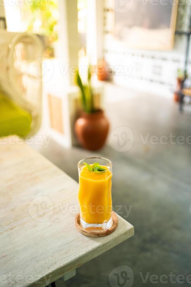 Fresh mango juice on table with luxury home blur background photo