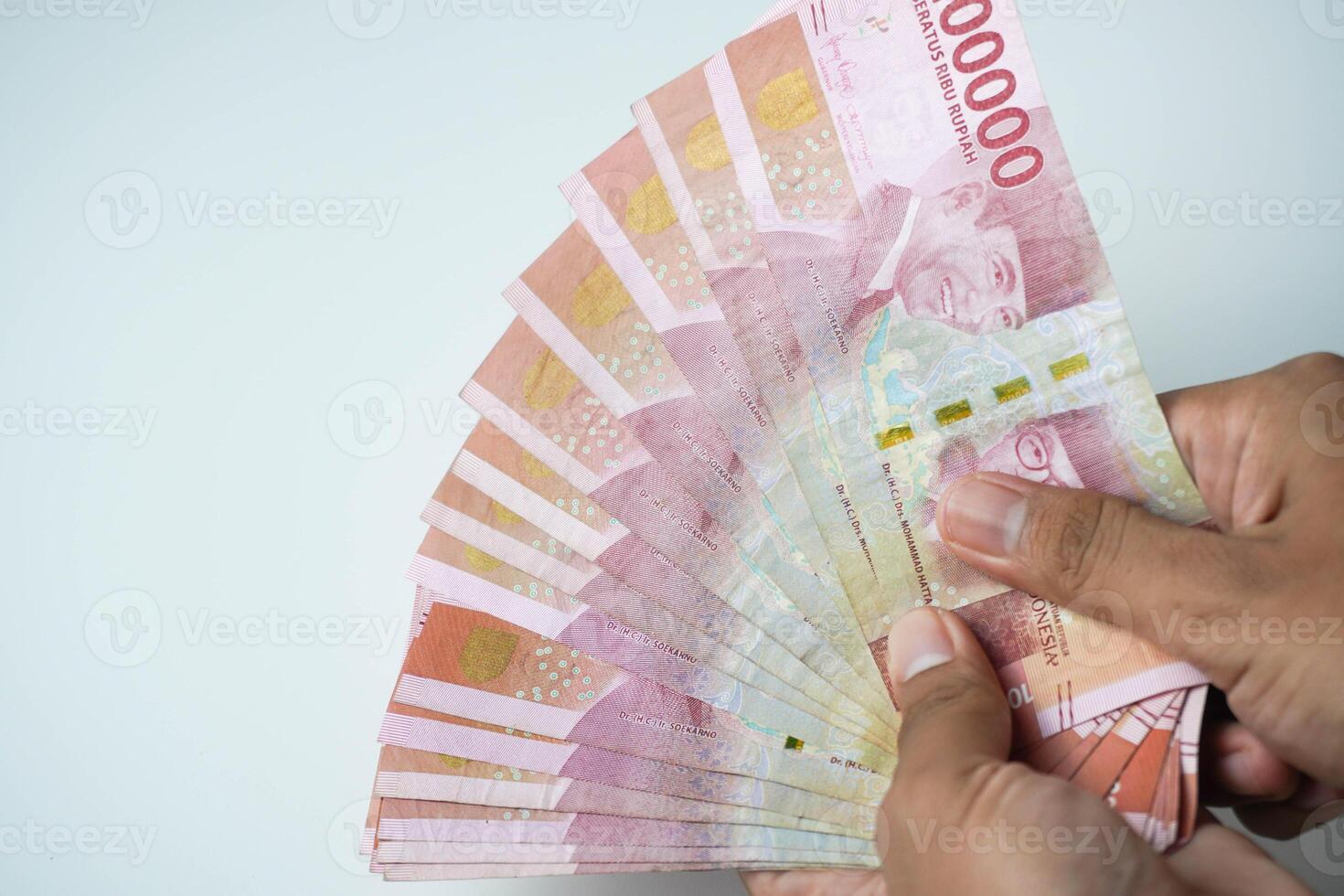 male hand holding a lot of indonesian money rupiah on a isolated white background. business concept ,financial concept photo