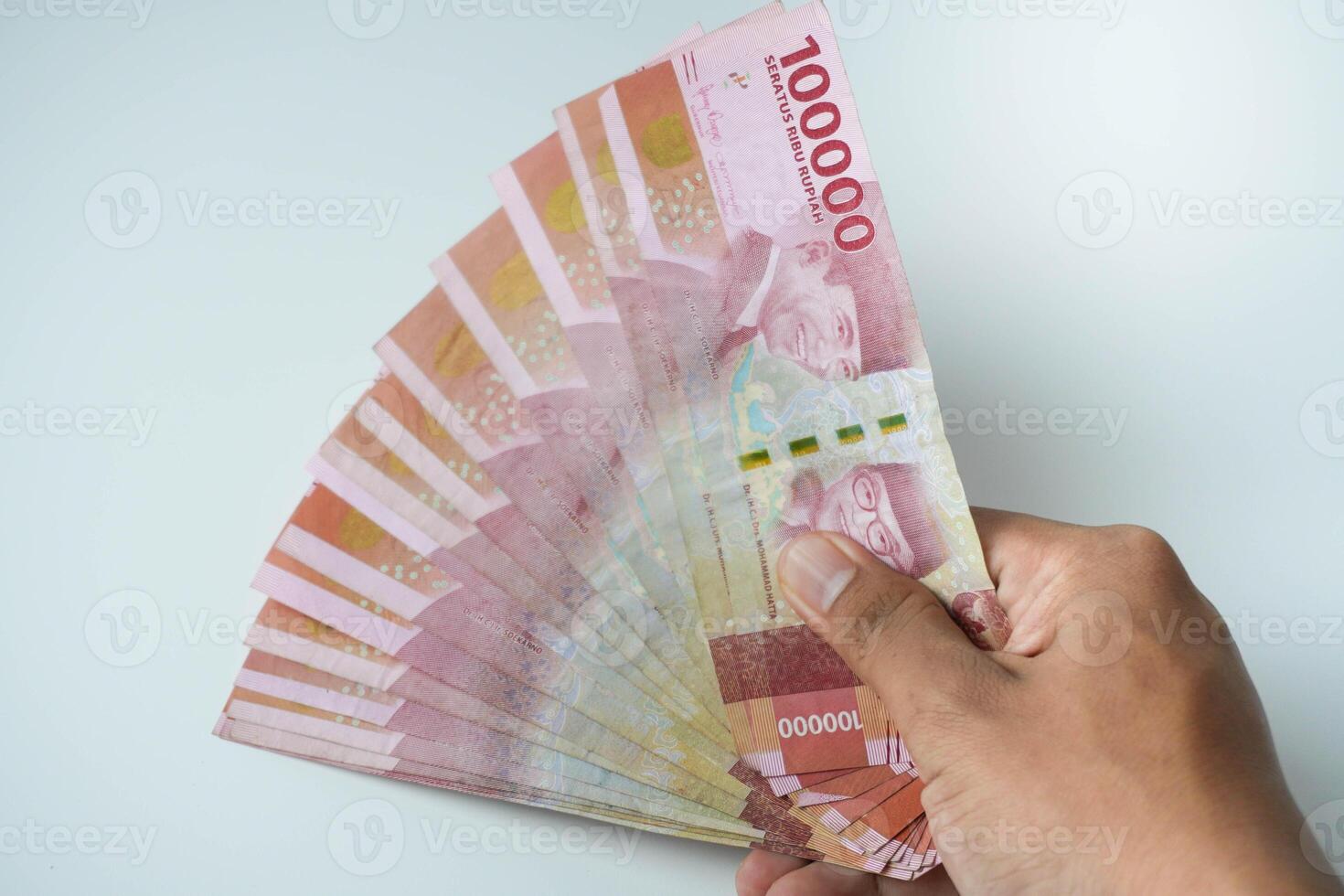 male hand holding a lot of indonesian money rupiah on a isolated white background. business concept ,financial concept photo