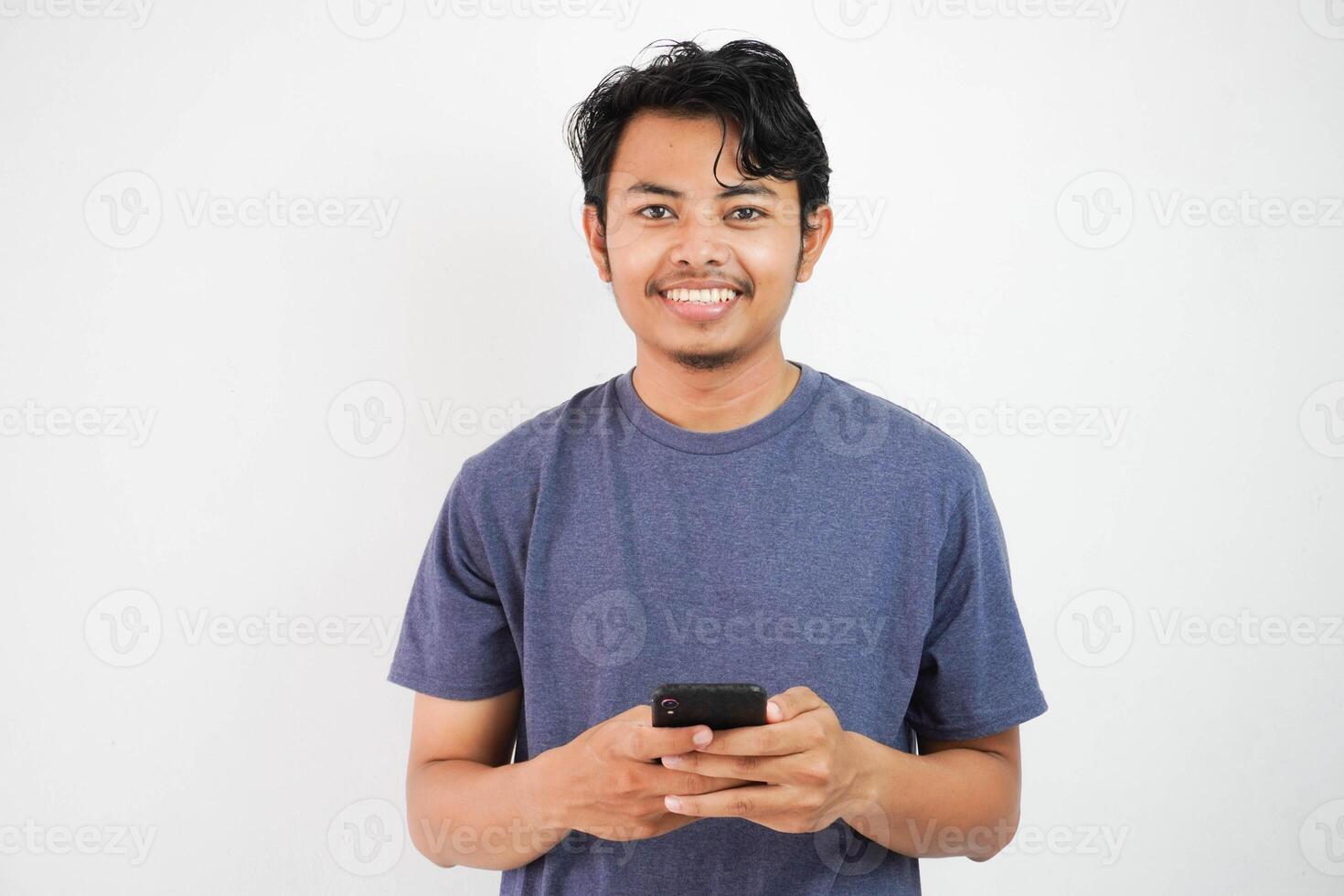 hermoso sonriente o contento asiático joven hombre casual atuendo en Armada camiseta participación inteligente teléfono chateando en blanco aislado antecedentes. foto